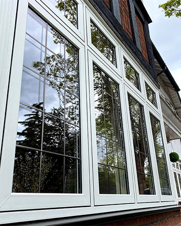 White flush casement windows with decorative leaded glass — the OMNIA flush look, supplied by WGS Glazing