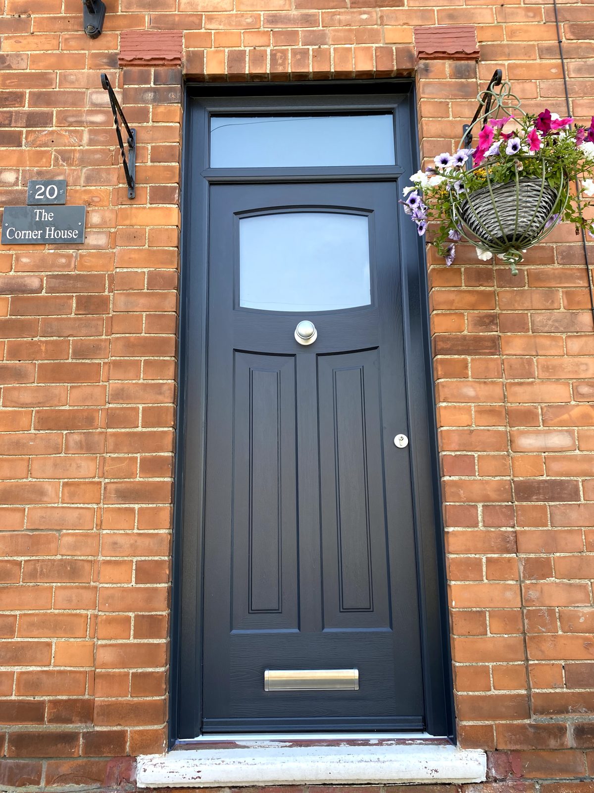 Dark grey traditional Rockdoor with arched top light and toplight on a brick property, supplied by WGS Glazing