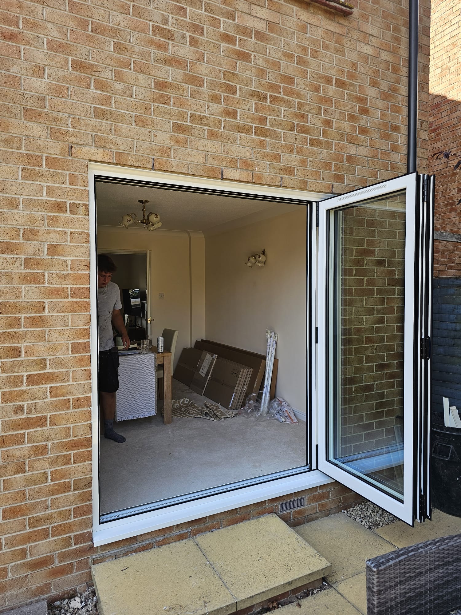 White bifold doors open on a residential extension, installed by WGS Glazing